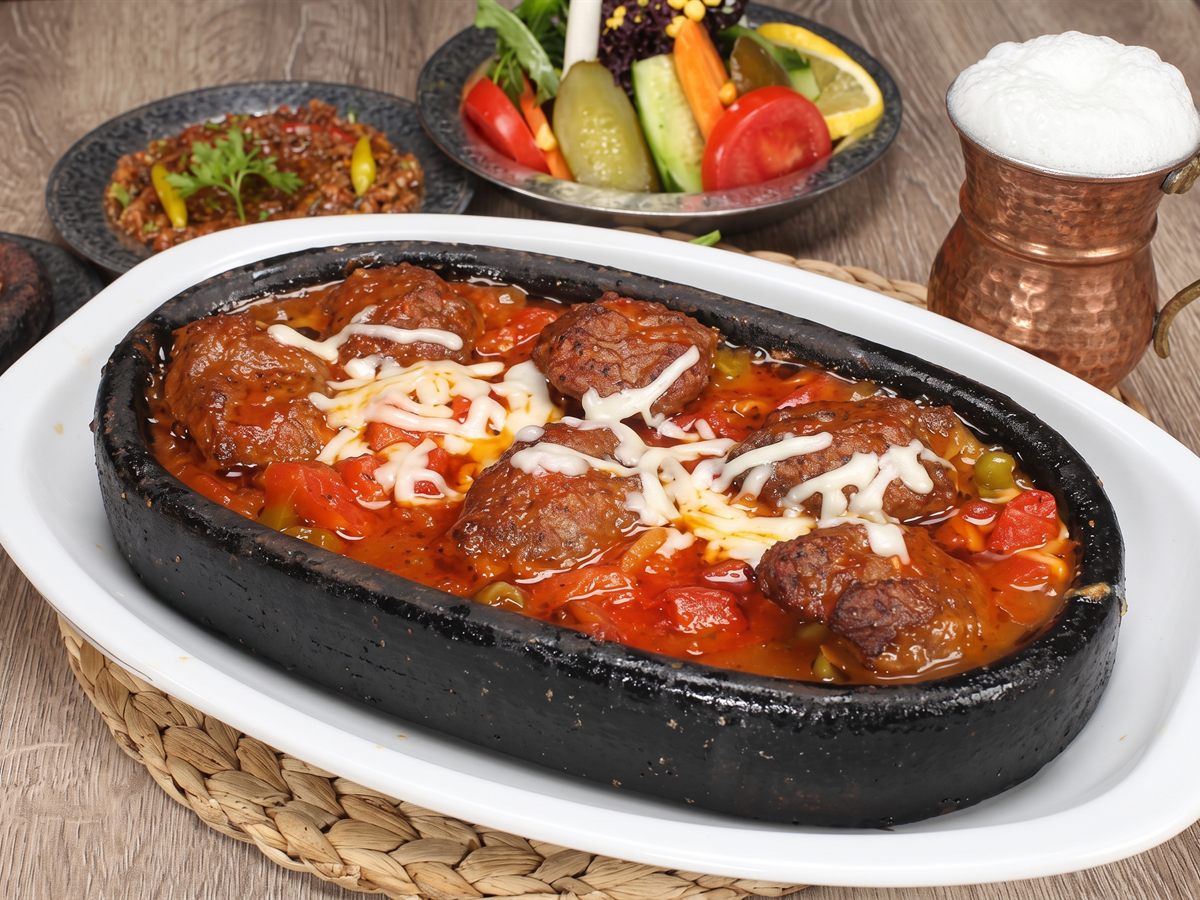 Taş kapta domates soslu kiremitte köfte, yanında salata ve ayran – Tutku Pide