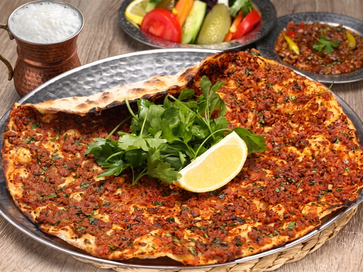 Tepside lahmacun, üzerinde maydanoz ve limon, yanında ayran – Tutku Pide